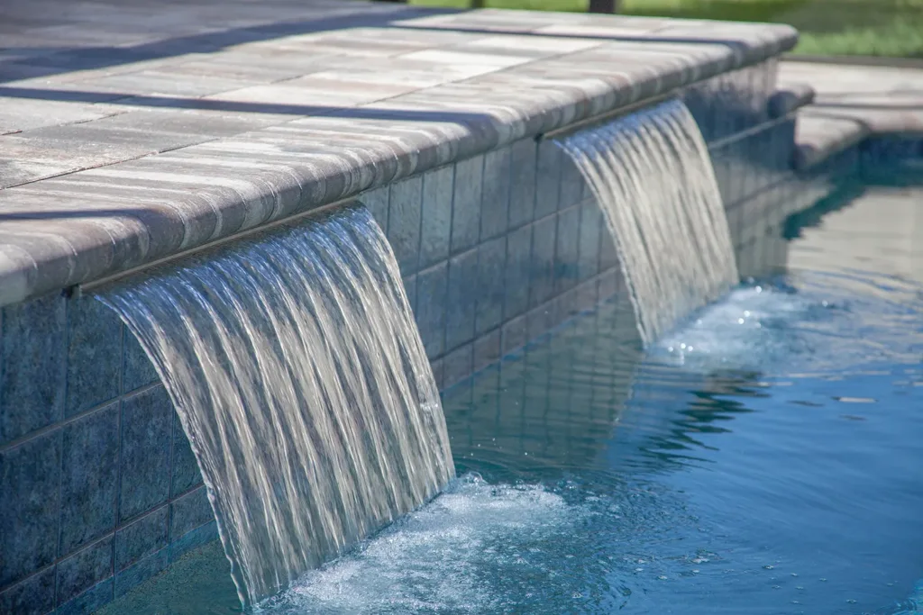 Twin sheer descent water features spilling into a custom pool