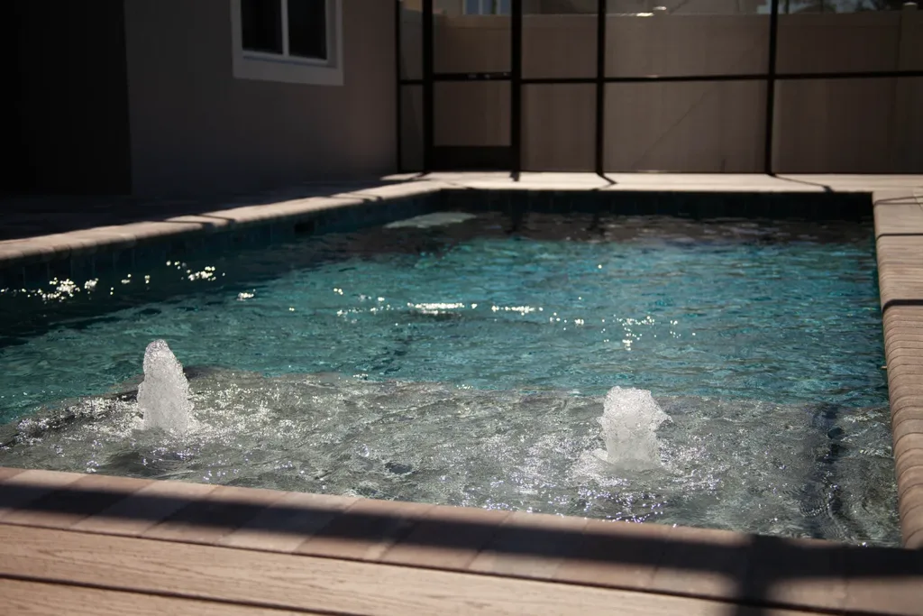 Custom pool sun shelf with bubblers inside a screened lanai