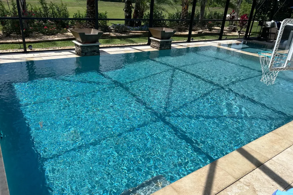 Geometric custom pool with a tanning ledge, umbrellas and paver deck